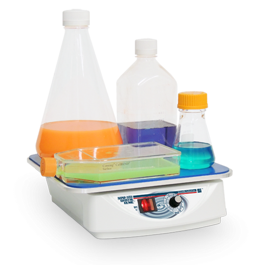 Lab hot plate with beakers containing colored liquids on a white background